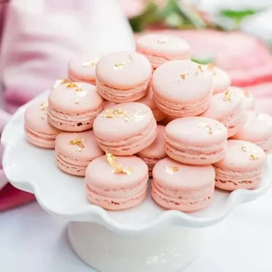 Macarons roses d’O’délices d’Élodie disposés en pyramide sur un présentoir blanc.