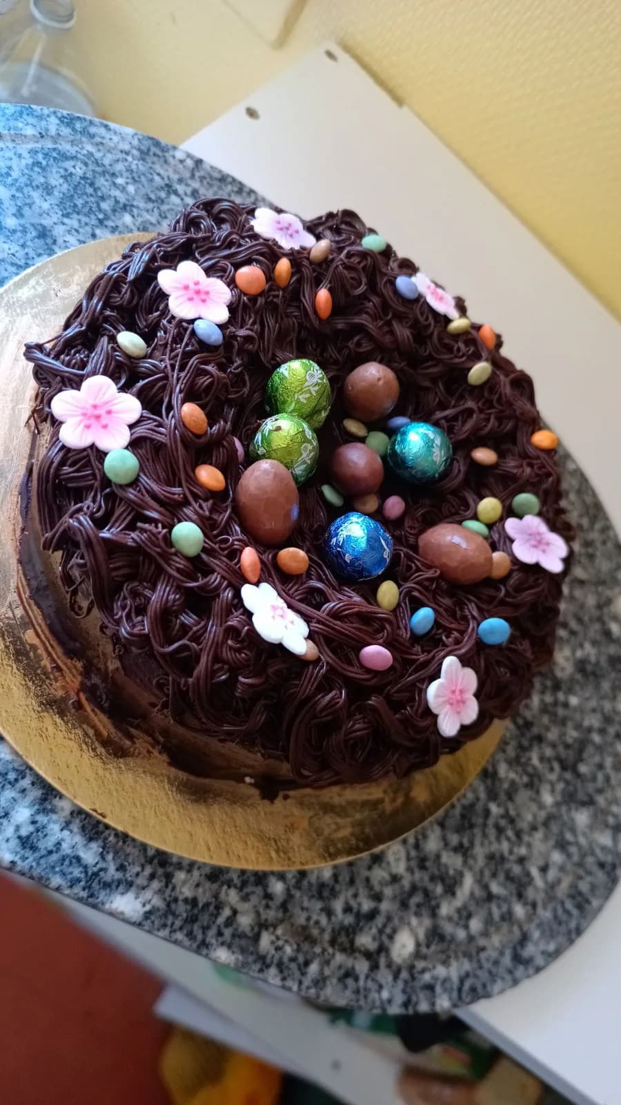 Gâteau de Pâques d’O’délices d’Élodie en forme de nid au chocolat, photographié sur un plan de travail.
