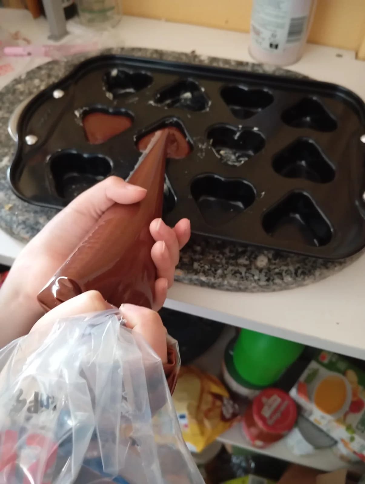Préparation de chocolats chez O’délices d’Élodie avec une poche au-dessus d’un moule en forme de cœurs.