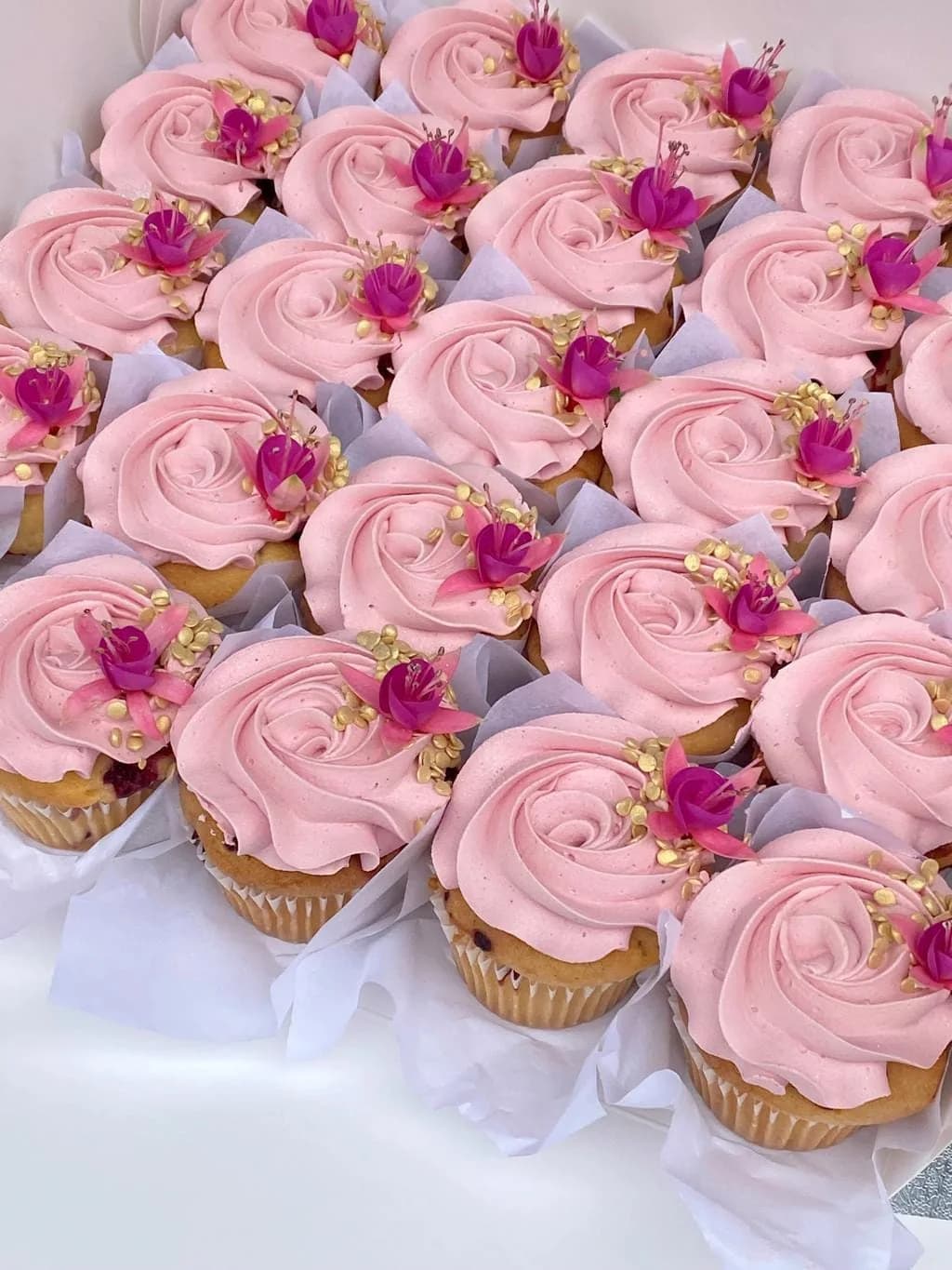 Cupcakes d’O’délices d’Élodie au glaçage rose et aux décors floraux, rangés dans une boîte blanche.